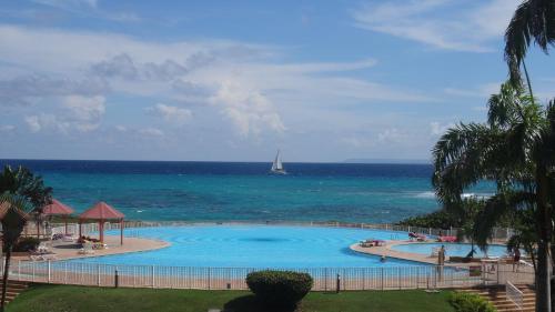 a large swimming pool next to the ocean with a sailboat at Holidays Guadeloupe -Paradise -Anse des Rochers in Belle-Allée