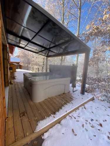 a bed under a roof on a deck in the snow at Le Hygge Chalet Gérardmer-Spa in Anould