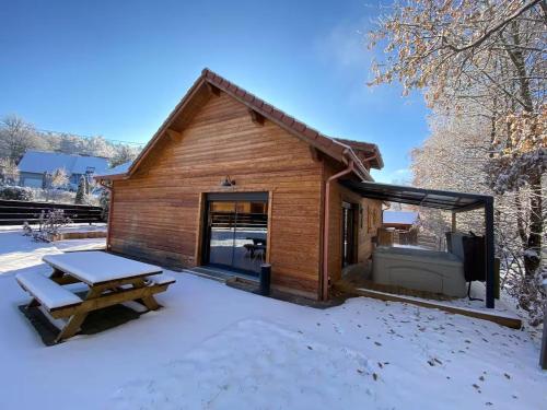 a log cabin with a picnic table in the snow at Le Hygge Chalet Gérardmer-Spa in Anould