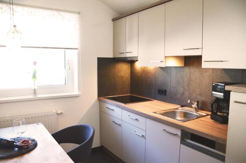 a kitchen with white cabinets and a sink and a table at Bettina in Ehrwald