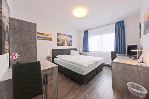 a hotel room with a bed and a desk at Hotel Hülsmann Garni in Niedersachsen-Stadland