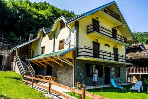 a man standing on the porch of a house at Apartments Vila Djurdja in Kopaonik