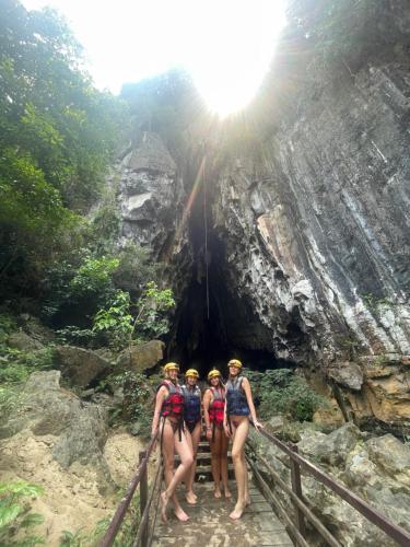 three people standing on a bridge in front of a cave at The Ridge Haven in Phong Nha