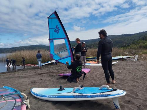a group of people standing on a beach with surfboards at Vichuquen Lodge y Marina in Vichuquén