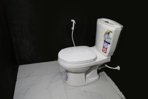 a white toilet in a bathroom with a black wall at Rainbow Budget Villa & Rooms in Mahiyangana