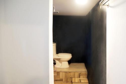 a bathroom with a toilet and a black wall at Rainbow Budget Villa & Rooms in Mahiyangana