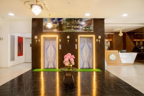 a lobby with two doors and a vase of flowers on a table at The Monarch Hotel Bagalur IT Park in Bengaluru