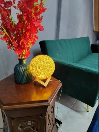 a green couch and a table with a vase of flowers on it at Village Retreat Jetty Kuala Perlis in Kuala Perlis
