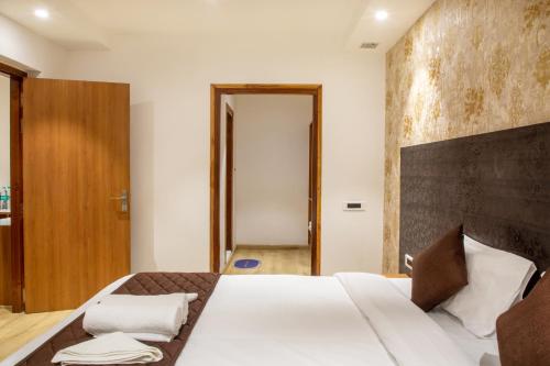 a bedroom with a large bed with a wooden headboard at The Monarch Hotel Bagalur IT Park in Bengaluru