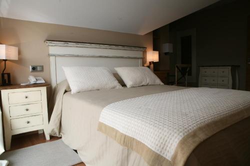 um quarto com uma cama grande com lençóis brancos e almofadas em Hotel Viento del Norte em Porto de Espasante