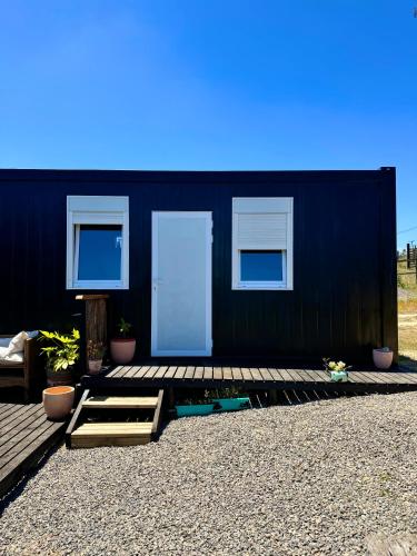 a black building with two white doors and potted plants at Ecos de Catrianca in Pichilemu