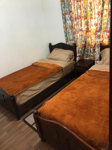 two twin beds in a room with curtains at Hagounia hotel in Tan-Tan
