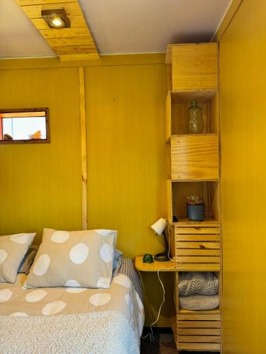 a bedroom with a bed and a yellow wall at Ecos de Catrianca in Pichilemu
