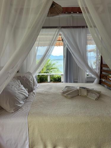 a bedroom with a bed with white curtains and a window at Cabana do Mar in Angra dos Reis