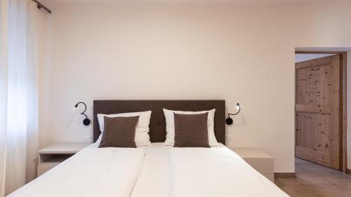 a bedroom with a large white bed with two pillows at Apartments Hofgarten in Caldaro