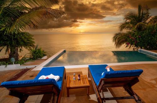 a pool with two chairs and a table with a view of the ocean at Culloden Cove in Whitehouse