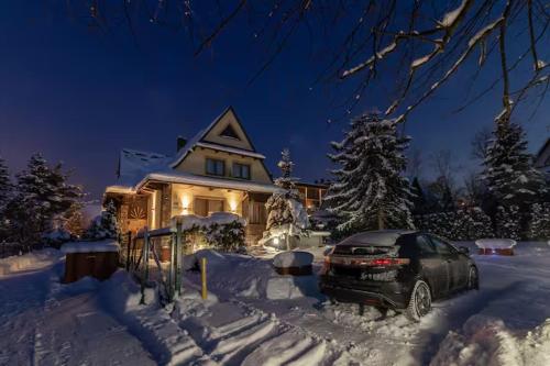 a car parked in front of a house covered in snow at Apartament Czarny Potok Lux Zakopane in Zakopane