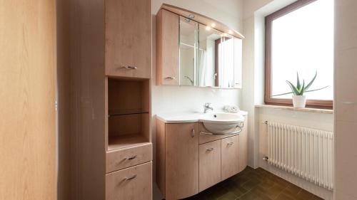 a bathroom with a sink and a mirror and a window at Apartments Hofgarten in Caldaro
