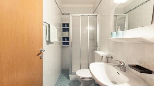 a white bathroom with a toilet and a sink at Apartments Hofgarten in Caldaro