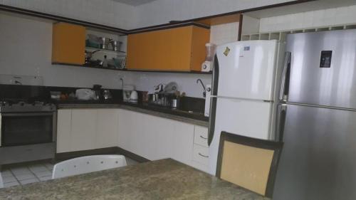 a kitchen with a white refrigerator and yellow cabinets at Casa Amarela in João Pessoa