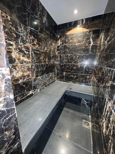 a shower with a bench in a room with marble walls at Avenue-3 Guest House in Islamabad
