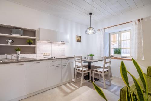 Una cocina con gabinetes blancos y una mesa y sillas. en Apartments Palma, en Cortaccia