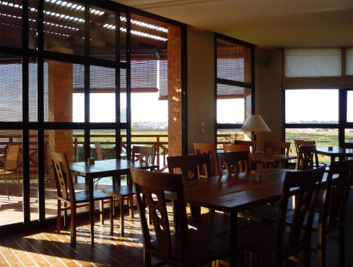 a dining room with tables and chairs and windows at Radisson Hotel Tamboho Waterfront Antananarivo in Antananarivo