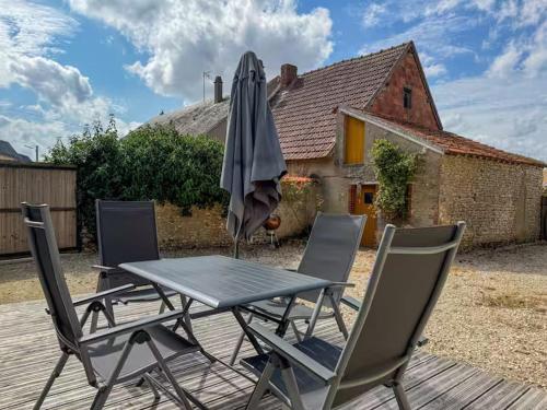 une table, des chaises et un parasol sur une terrasse dans l'établissement Maison charmante et moderne près de Chartres, à Sours