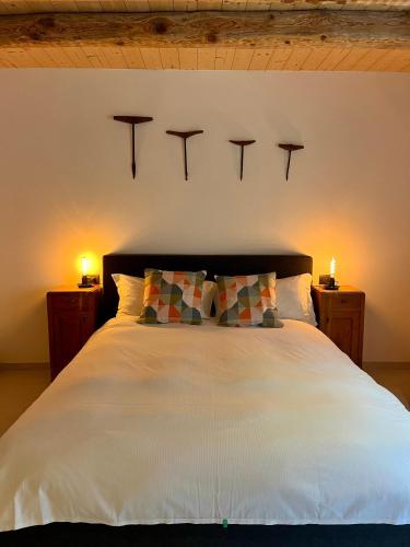 a bedroom with a white bed with two lights on the wall at Appartamenti La Rocia in Rocca Pietore