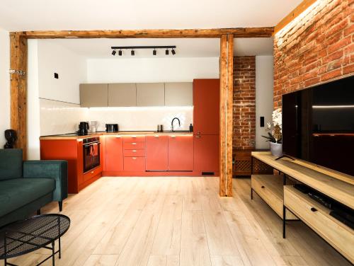 a kitchen with red cabinets and a brick wall at Brick and Wood Apartment in Bydgoszcz