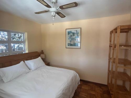 a bedroom with a bed and a ceiling fan at The Milkwood Place in Kommetjie