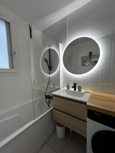 une salle de bain blanche avec un lavabo et un miroir dans l'établissement Appartement La Perle Urbaine, à Bourges