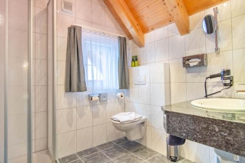 a bathroom with a toilet and a sink and a shower at Hotel Garni Alpenhof in Ischgl