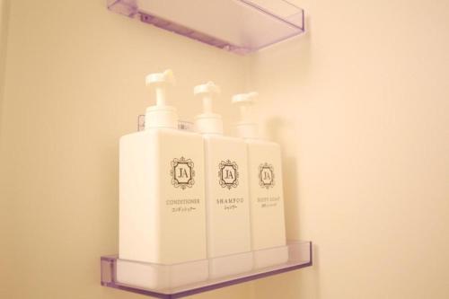three bottles of soap on a shelf on a wall at JA Hotel Midoribashi -the bresidence- in Osaka