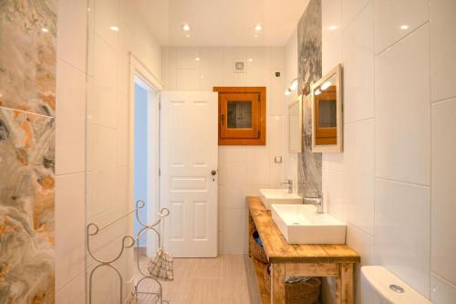 a white bathroom with a sink and a mirror at Bee Tree Villa in Corfu