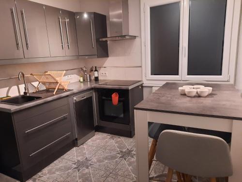 une cuisine avec des placards noirs et une table avec un évier dans l'établissement Appartement familial à 2 pas du lac, à Annecy