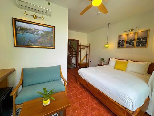 a bedroom with a bed and a chair in it at Blue Tropical House Hội An in Hoi An