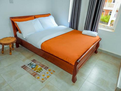 un letto con una coperta arancione e una finestra di 5 Stones a Kigali