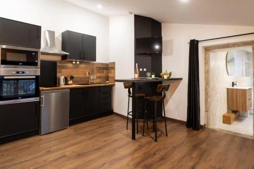 - une cuisine avec des armoires noires et un bar dans l'établissement Le Sigorgne Centre-ville Gare, à Mâcon