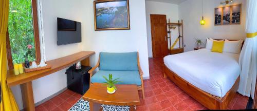 a bedroom with a bed and a desk and a chair at Blue Tropical House Hội An in Hoi An