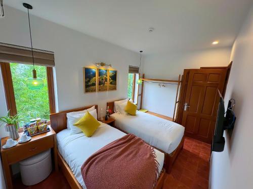 a bedroom with two beds and a window at Blue Tropical House Hội An in Hoi An