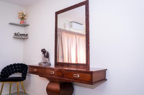 a mirror on top of a dresser with a chair at High Court Self Catering Apartments in Nelspruit