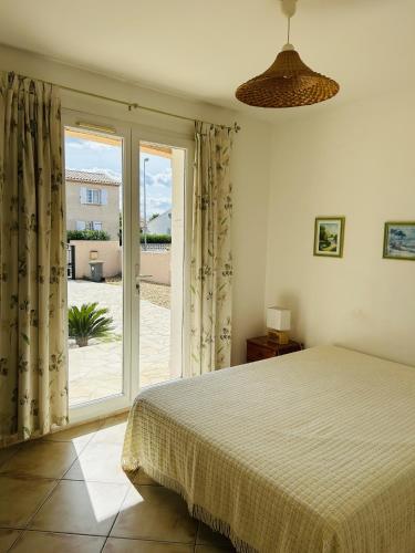 une chambre avec un lit et une porte coulissante en verre dans l'établissement La Villa Harmony, à Portiragnes