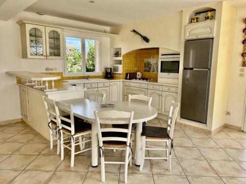 une cuisine avec une table et des chaises dans l'établissement La Villa Harmony, à Portiragnes