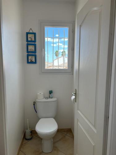 une salle de bain blanche avec toilettes et fenêtre dans l'établissement La Villa Harmony, à Portiragnes