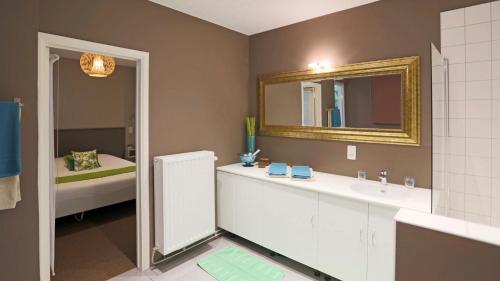 a bathroom with a sink and a mirror and a tub at Aparthotel Liège in Liège