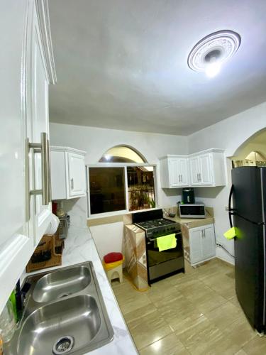 a kitchen with white cabinets and a black refrigerator at Casa Tipo Villa, Piscina, Playas De RSJ a 4 min in Río San Juan