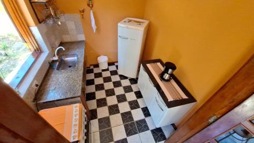 une petite cuisine avec un réfrigérateur et un sol à damier dans l'établissement Casa de campo Sanloá, à Parati