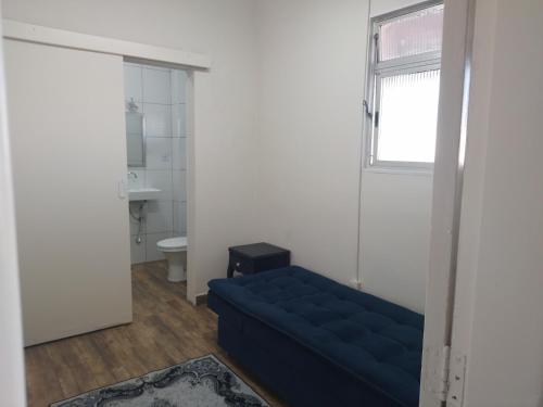 een woonkamer met een blauwe bank en een raam bij Cobertura com churrasqueira São Vicente in São Vicente