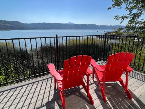 two red chairs sitting next to a body of water at Clear Lake Cottages & Marina in Clearlake
